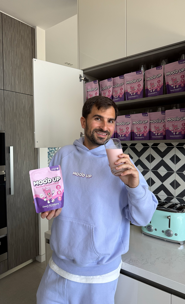 Person holding a Moo’d Up pouch and a glass of chocolate milk